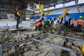 The police and rescuers inspect the damage at an indoor arena in San Remigio town, Cebu
